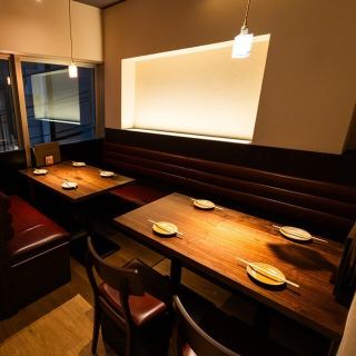 落ち着きあるテーブル席。厳選した日本酒を合わせて。音・香り・炎に包まれながら、特別な一皿とお酒で、心も身体も満たされるひとときをお過ごしください