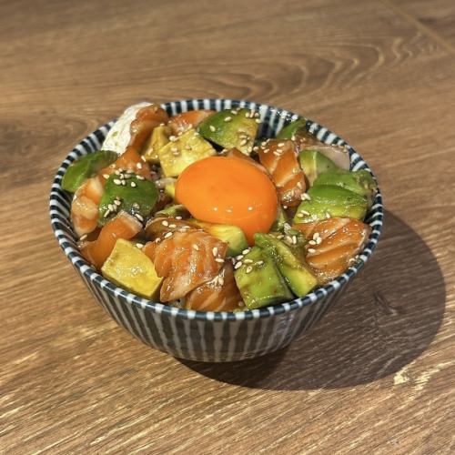Salmon and avocado poke bowl topped with egg yolk