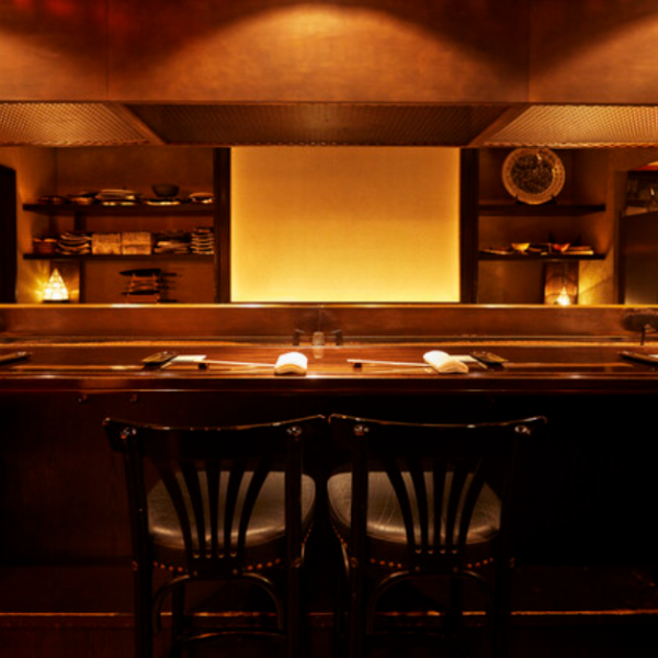 【カウンター席】エントランスを抜けると、目の前に広がるのはライブ感あふれるカウンター席。2名掛けのテーブルを3卓ご用意しており、レイアウトを調整することで3名様～6名様まで柔軟にご案内可能です。デートや記念日などお二人でゆっくり過ごすディナーや、グルメ好きな方にもお勧めです。