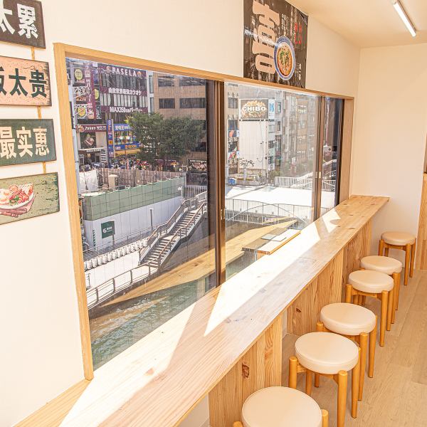 ≪心地よい明るさが差し込む窓際のカウンター席≫大きな窓からは、賑やかな街並みが一望でき、食事を楽しみながら外の景色を楽しむことができます。シンプルで温かみのある木のテーブルと、丸みを帯びた椅子が心地よい空間を演出♪洗練されたデザインの中で、友人や家族と楽しいひとときを過ごすのに最適です。