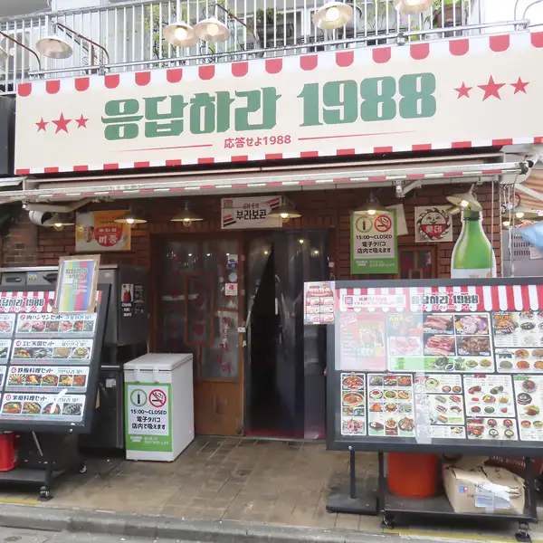【ドラマの世界観そのままに】一歩足を踏み入れれば、そこは1988年の韓国。レトロで温かみのある内装と、店内に流れるドラマの映像がノスタルジックな雰囲気を演出します。広々としたテーブル席は連結可能で、少人数の女子会から大人数の宴会まで幅広く対応。新大久保にいながら旅行気分を味わえる特別な空間です。