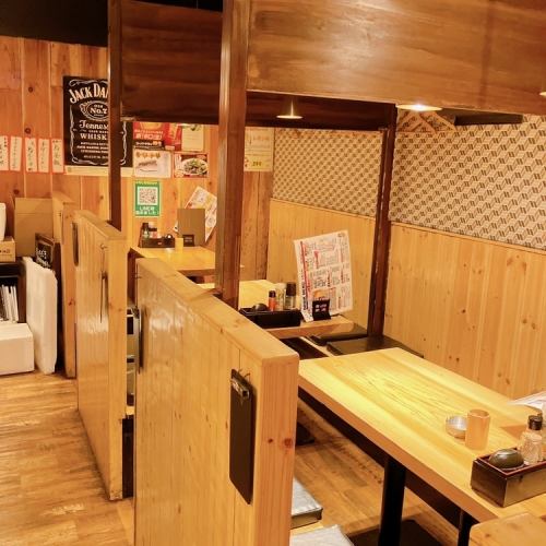 <p>店内はオレンジ色の温かい明かりで照らされており、木をあしらったテーブル席が配置されています。4名様が座れる広々としたテーブルは、ゆったりとした空間でお食事を楽しむことができます。</p>