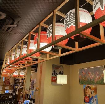 通路一面に飾り付けた紅白提灯の灯りがワクワクと楽しい気分にさせてくれます！明るい提灯の灯りに照らされたカウンター席は、一人でも入りやすく、楽しい雰囲気を演出しています。お一人様のご利用にも、デートなどの特別なシーンのご利用にもぴったりなお席です。友人や大切な人とともに特別なひとときをお過ごしください