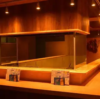 店の中心に配置されたカウンター席は、職人の手仕事を間近で楽しめる特等席。鮨を握る所作や藁焼きの臨場感を感じながら、出来立ての一品を味わえます。お一人様やデート、しっぽりと飲みたい夜にも最適。落ち着いた照明と木の質感が心地よい空間です。