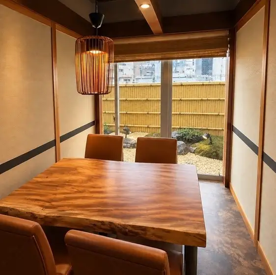 接待やデート、各種ご宴会にふさわしい完全個室を備えた和の空間が広がる店内です。無垢の一枚板を使用した重厚なテーブルや、柔らかな間接照明が落ち着いた雰囲気を演出します。窓から覗く竹垣など、視覚からも和の情緒を感じ取れる設計となっており、大切な方との記念日にも適したプライベートな環境をご案内しています。
