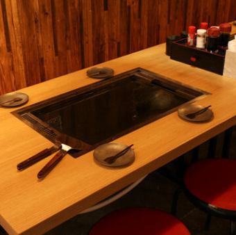 ゆったりと設計された4名掛けのテーブル席です。中央に配置された鉄板を囲みながら、皆様でワイワイともんじゃを焼く楽しさを味わえます。全席に鉄板を備えており、自分たちのペースで熱々の料理を囲めます♪また、ご家族での利用も大歓迎！