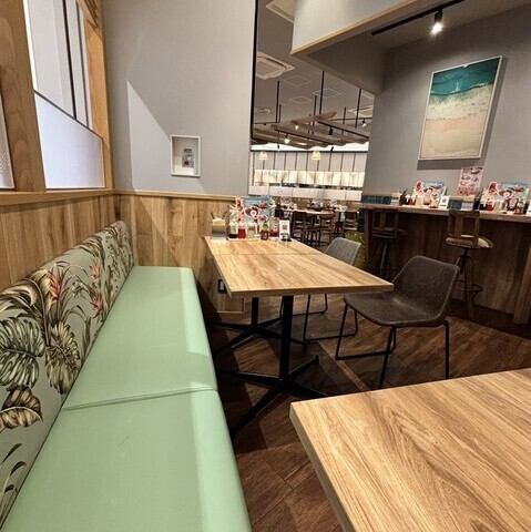 <p>【南国のくつろぎ空間】淡いミントグリーンのソファと木目調のテーブルが、明るく開放的な雰囲気を醸し出します。壁にはトロピカルな絵画が飾られ、まるでハワイのリゾートカフェでくつろいでいるような心地よさをお楽しみいただけます。</p>