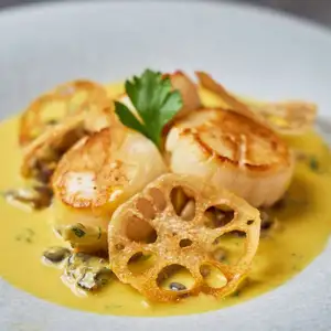 Pan-seared scallops with seasonal vegetables, autumn mushrooms, and saffron sauce.