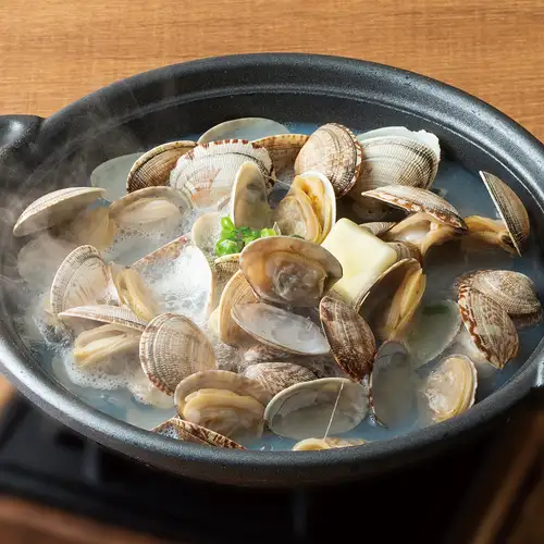 Steamed clams in their shells in a ceramic pot